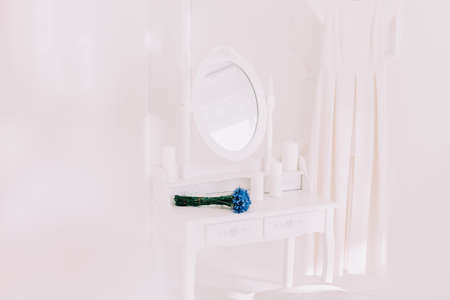 white dressing table with mirror, dress and bouquet of flowers.の写真素材