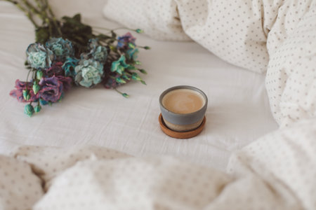 Good morning, Flat lay composition with coffee cup, blue flowers and warm blanket in cozy bed, top view.の写真素材