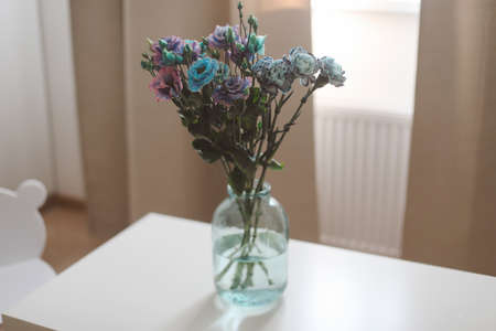 bunch of blue and purple flowers in a jar on the table in a sunny room, minimal home decor.の写真素材