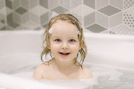 small girl playing with rubber duck toy while bath.