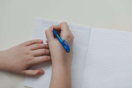 pupil's hands writing in open notebook, top view, copy space.の写真素材