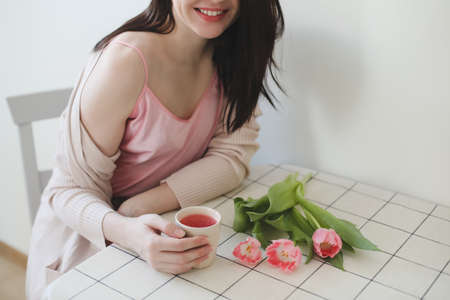 romantic tender portrait of a young woman with pink fresh tulipsの写真素材