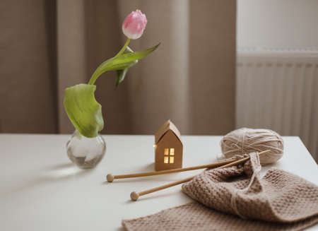 cozy home interior decor with a chair, plaid, table and knitting needles with threads, beige yarn.の写真素材