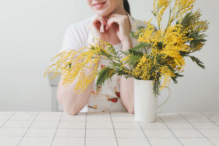 Beautiful young smiling woman with mimosa flowers on white backgroundの写真素材