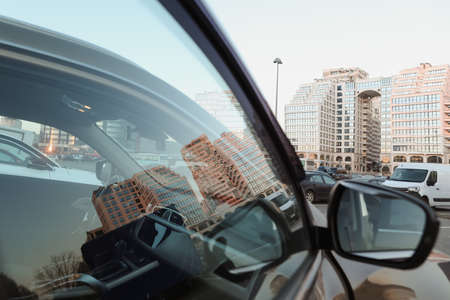 The urban landscape reflected in car mirror. Exteriors of typical modern apartment buildings against a blue sky with cloudsの写真素材