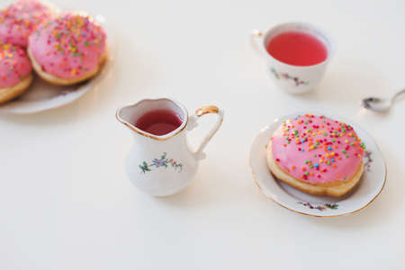 holiday, birthday party composition with colorful pink glazed donuts on white table, flatlay top...