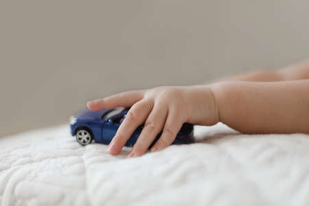 close-up of child hand playing with toy car. hand of a little kid pushing a plastic toy car on the white background.の写真素材