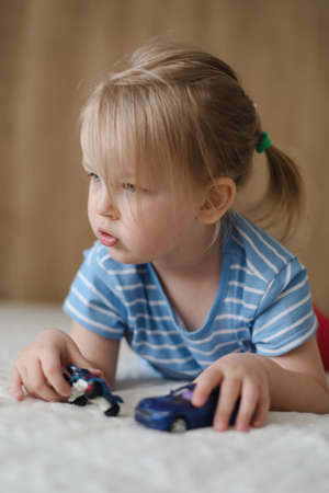 Portrait of child playing with toy cars indoors. Toddler having fun.の写真素材