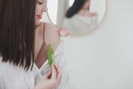 spring portrait of a young woman with pink fresh tulip on white background.の写真素材