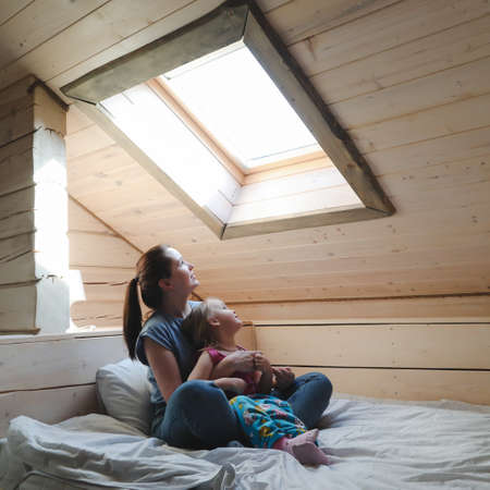 Portrait of enjoy happy family mother and little girl hugging, smiling, playing and having good time in a cozy room at home.の写真素材