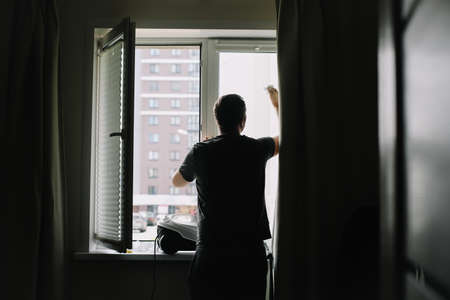 Man washing and cleaning window at home. Housework and housekeeping, home hygiene