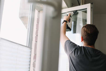 Man washing and cleaning window at home. Housework and housekeeping, home hygiene