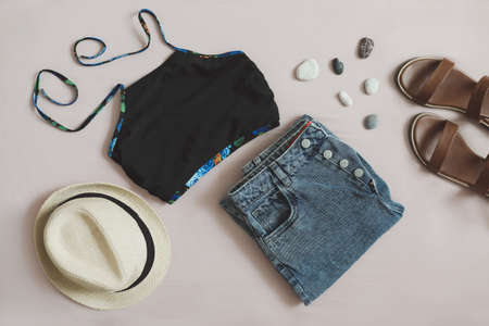 flat lay composition with female top, denim shorts, sandals and a wicker rattan bag on beige background top viewの写真素材