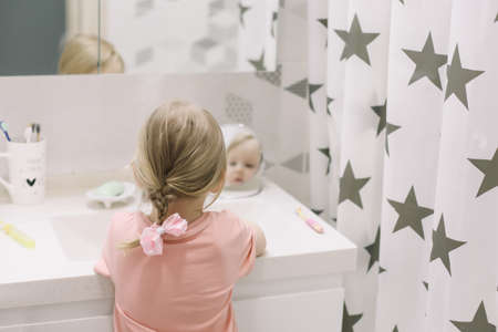 Cute toddler girl brushing teeth in the bathroom. Teeth cleaning, dental care
