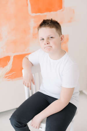 Close up portrait of a happy cute boy in a white t-shirt looking at camera on a colorful background....