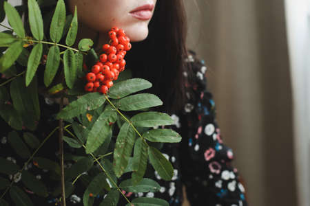 beautiful female lips with red lipstick and red rowan berries close-up. Professional makeup. Autumn conceptの写真素材