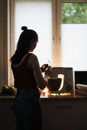 Housewife woman baking at home using kitchen planetary mixer in a cozy kitchen