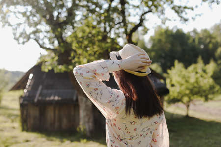 romantic portrait of a young woman in straw hat and beautiful dress in the countryside in summerの写真素材