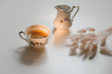 cup with coffee and milk jug on a white wooden background, closeup. Energy breakfast, morning routine conceptの写真素材