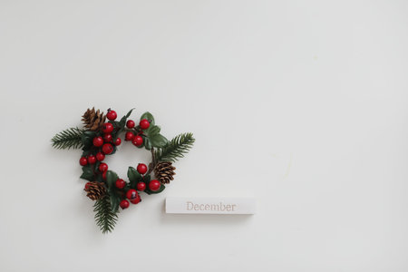 Wooden calendar with word DECEMBER and New Year and Christmas decorations on white background, top...
