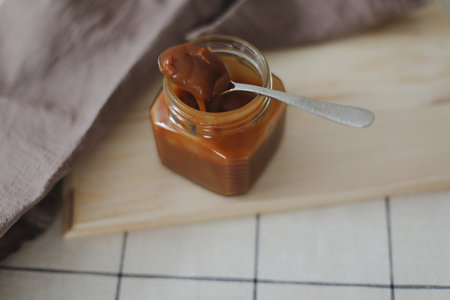 Homemade salted caramel sauce in jar on rustic wooden table.の写真素材