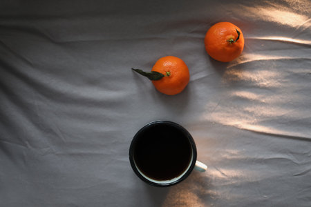 Winter cozy concept. Cup with coffee and tangerines on the bed. Copy space. Flat lay, top viewの写真素材