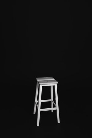minimalist wooden chair against black background. Concept modern interior and design furniture in room. High stool in loft style. Retro Bar chair. Vintage wooden metal chairの写真素材