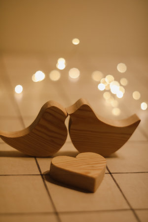 two wooden birds and heart made by bokeh lights background. Valentines day, Wedding, Easter card with wooden figures of birds, home decorの写真素材