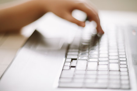 Close-up of male hands typing on laptop keyboard indoors. Businessman working in office or student...