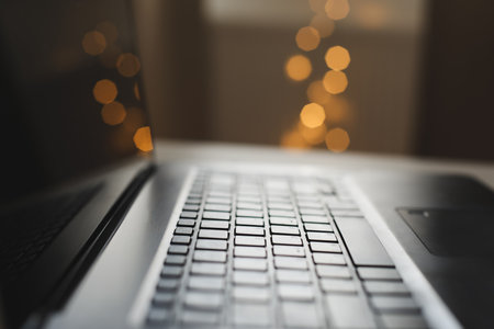 Close up of laptop keyboard with blank screen on a table by blurry bokeh lights background in the house or office modern, sunlight in morningの写真素材