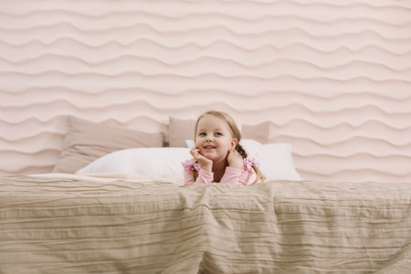 Morning of little girl in a comfortable bedroom. Happy child girl having fun and plays in bedの写真素材