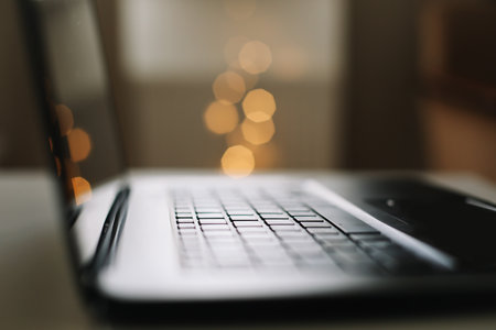 Close up of laptop keyboard with blank screen on a table by blurry bokeh lights background in the house or office modern, sunlight in morningの写真素材