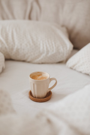 breakfast in bed, a white coffee cup on crumpled clean factory pastel linen in a hotel room. Light cozy bedroom, good morningの写真素材