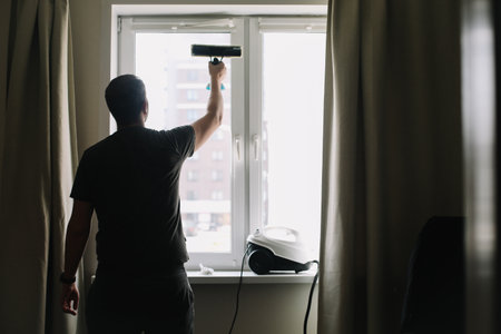 Man washing and cleaning window at home. Housework and housekeeping, home hygieneの写真素材