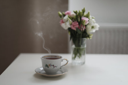 Home cozy still life scene. Table composition with cup of coffee, tea and flowers. Beautiful floral bouquet with rosesの写真素材