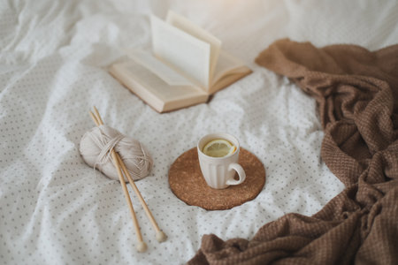 Cozy morning still life with a coffee cup, candle, needles and a woolen yarn in white bed. Knitting...