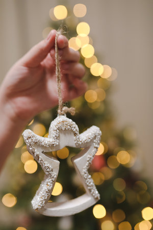 Cute toy angel and fir cone hanging and decorating a Christmas treeの写真素材