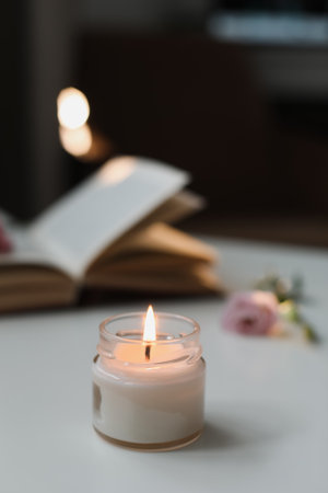 Still life details in home interior of living room. Open book with flower, burning candle with smoke. Read and rest. Cozy homeの写真素材