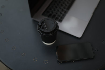 Desk office with laptop, phone, coffee cup, pen on black table. Flat lay top view copy space. Home office. Inspiration moment, workspace or coffee break in the morning. selective focus.の写真素材