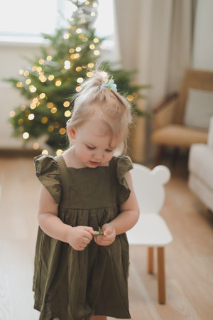 Little girl decorating christmas tree with toys and baubles. Cute kid preparing home for xmas celebration.の写真素材