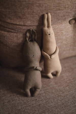 Cute baby soft toys bunnies together, brown copyspace background. Handmade childrens toy - soft crocheted bunny rabbits - concept of happy childhood.の写真素材