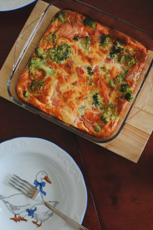 Frittata with spinach, red fish and cheese on wooden table. Portion on a plate. Eggs scrambled on the wooden table.の写真素材