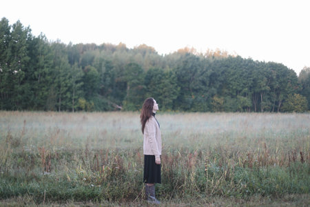 Young woman standing in a misty field in the morning. Autumn morning and sunrise on a misty field.の写真素材