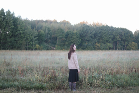 Young woman standing in a misty field in the morning. Autumn morning and sunrise on a misty field.の写真素材