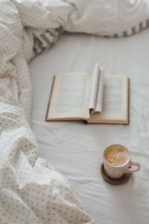 Cozy morning composition with a coffee cup and a book with pages folded into a heart shape in bed
