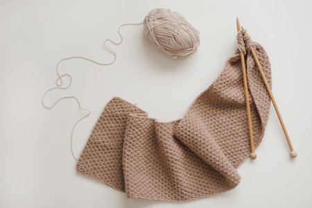 Knitting needles with threads, beige yarn. Hobby for women concept. Knitting accessories