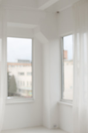 Abstract blurred modern workspace background, white indoor interior with window with copy space. Blurry backgrounds. Blurred view of light room with big windowの写真素材