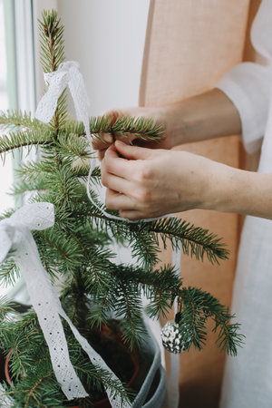 Woman hands decorating christmas tree. Atmospheric time. Holiday, Christmas and New Year family celebration concept.の写真素材
