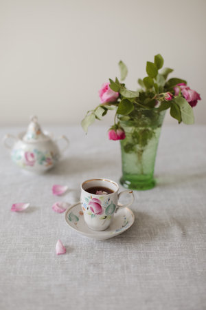 Moody summer still life. Table composition with cup of coffee, tea and beautiful floral bouquet with pink rosesの写真素材