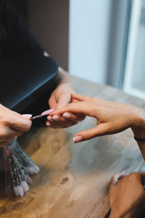 Woman getting nails done in beauty salon. Nail care procedure in a beauty salon. Female hands and tools for manicure, process of performing manicure in beauty salon.の写真素材